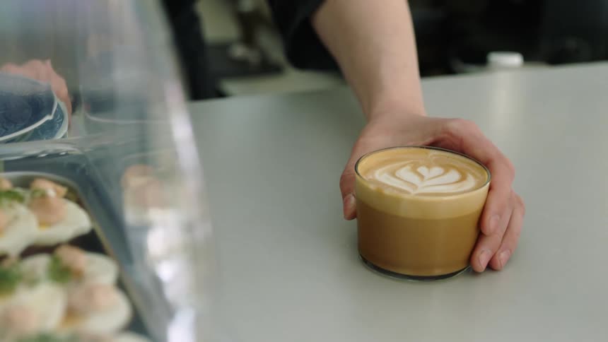 A person is making a coffee at a coffee shop
