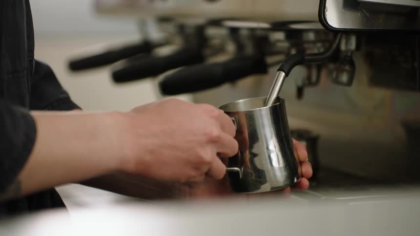 Barista steaming milk with an espresso machine