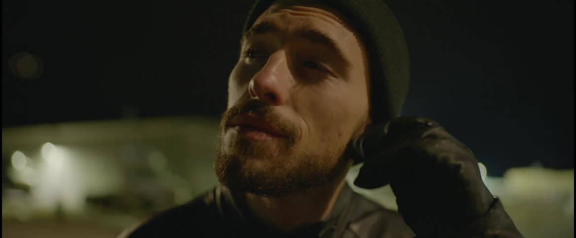Young bearded man wearing a beanie puts earbuds and starts listening to music