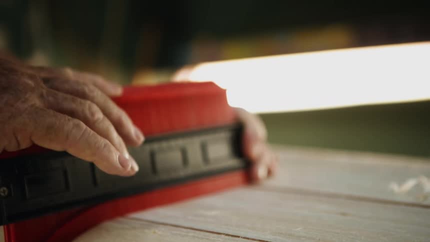Craftsman measuring a wooden structure with a ruller inside a workshop
