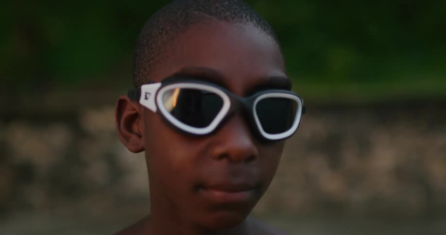 A boy is standing outdoors and wearing sunglasses