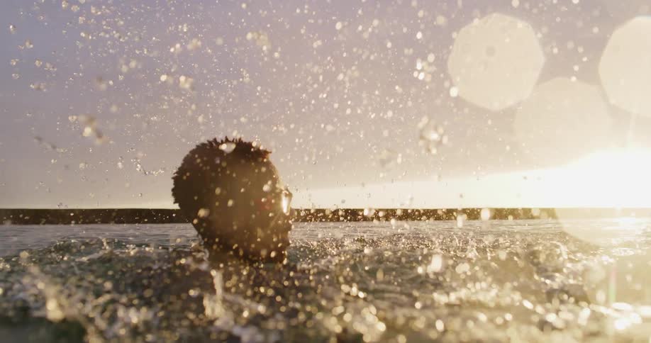 Two young teenage boys diving and swimming in the ocean waters at sunset