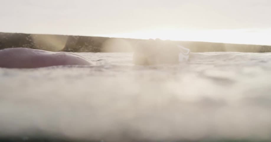 A person is swimming in the ocean water at dusk