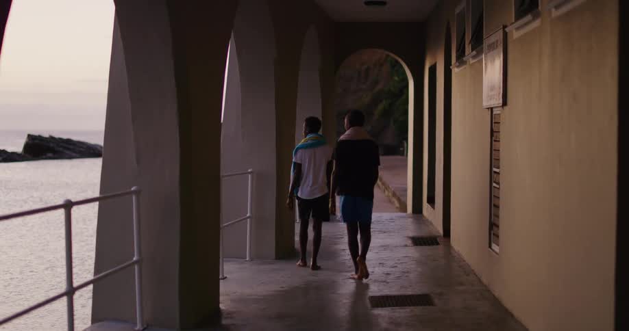 Couple of teenage boys walking on a hallway near to the beach at sunset