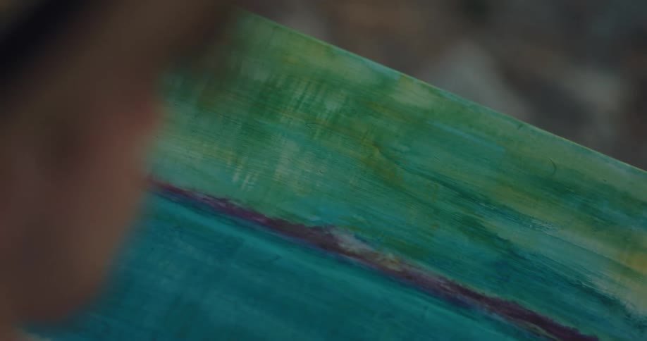 A man with a hat painting on a canvas with a paintbrush