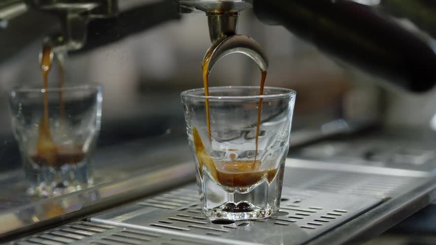 Espresso is pressed into a glass shot glass