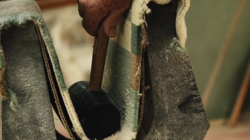 Person picks up mallet sitting in sling near mirror