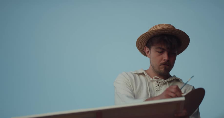 A man outside paints on a canvas