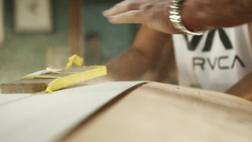 Two men use a mallet and a piece of wood to remove a large piece of wood from a table