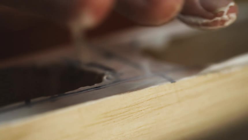 Carpenter uses his fingers to apply white glue on a piece of wood