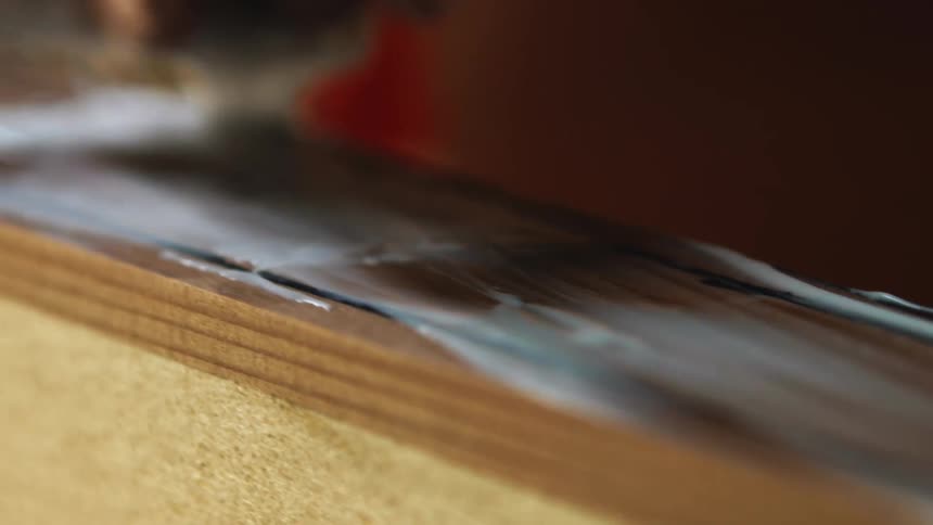A person in a room using a sponge to rub paste on wood