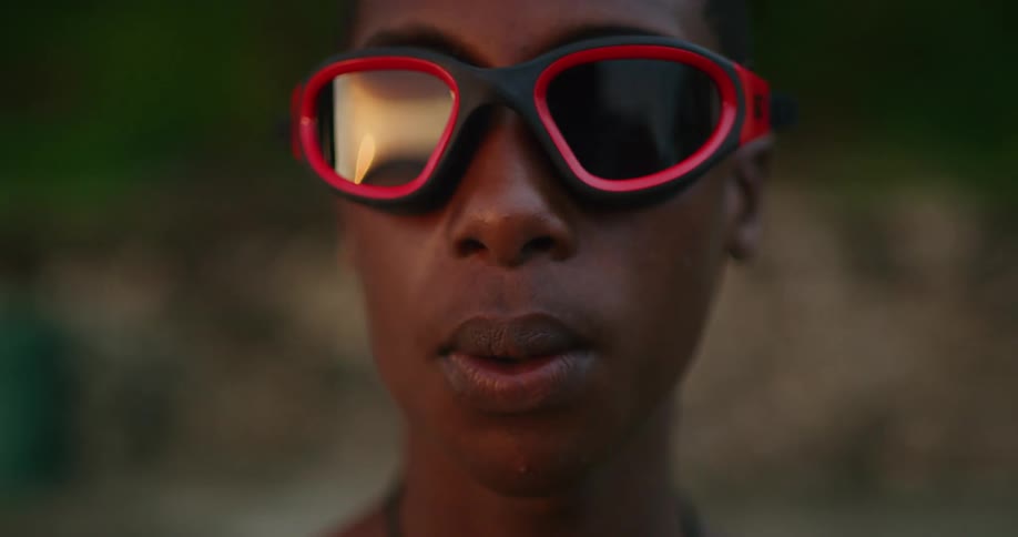 Young person wearing black goggles looking at the camera at sunset