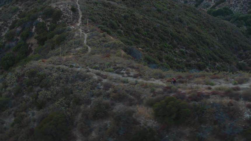 A person riding a bicycle on a dirt path on a cliff