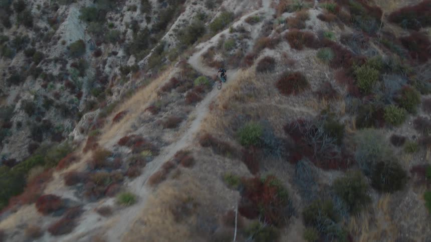 A cyclist is riding a bicycle on a trail across the top of a mountain ridge
