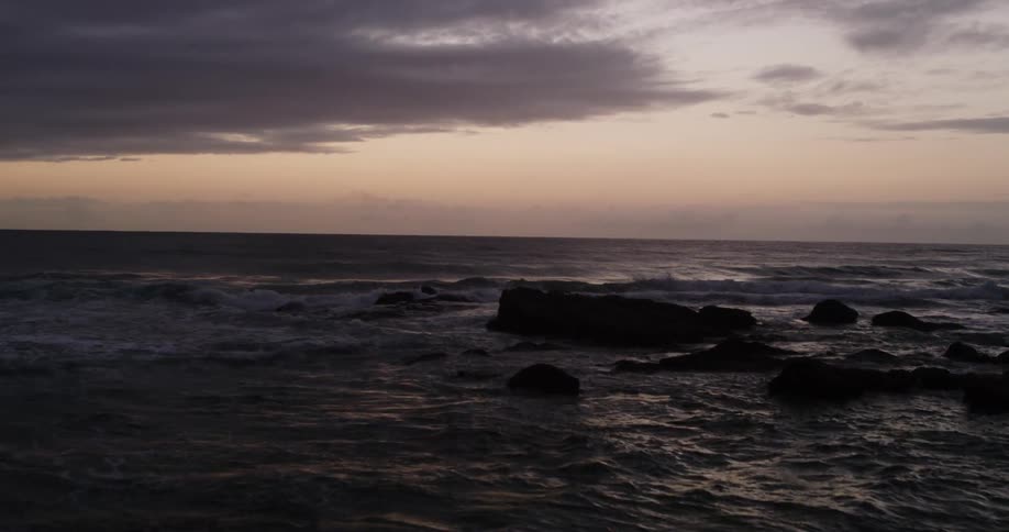 Rough water and waves crashing into rocks under a dark cloudy sky