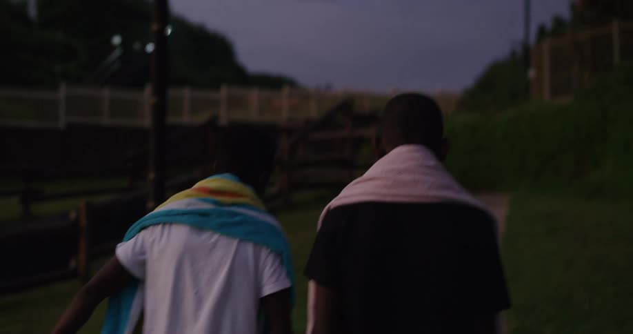 Two children are walking outdoors in a neighborhood at night