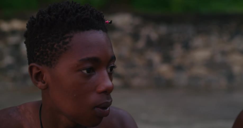 Young man sitting on a beach talking to friends at sunset