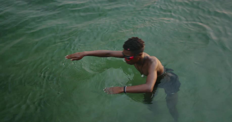 Young teenage boy wearing goggles practices swimming in the ocean