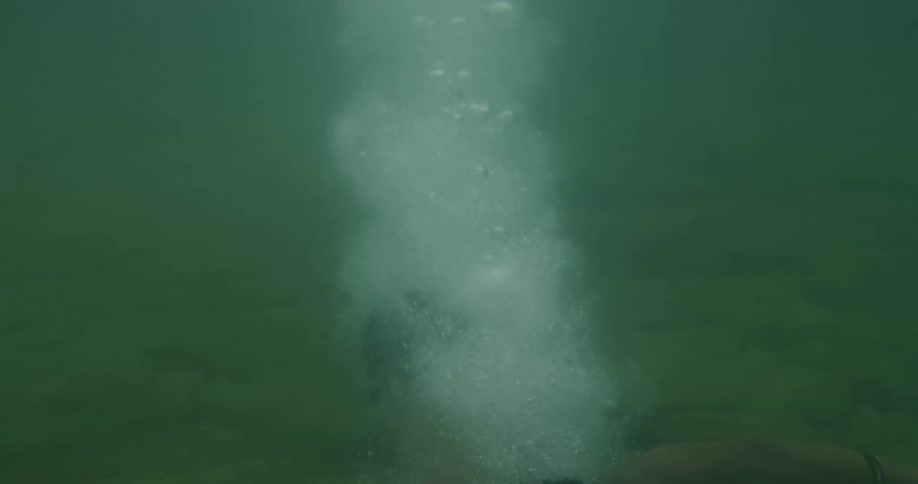 A boy jumps off the ladder diving underwater