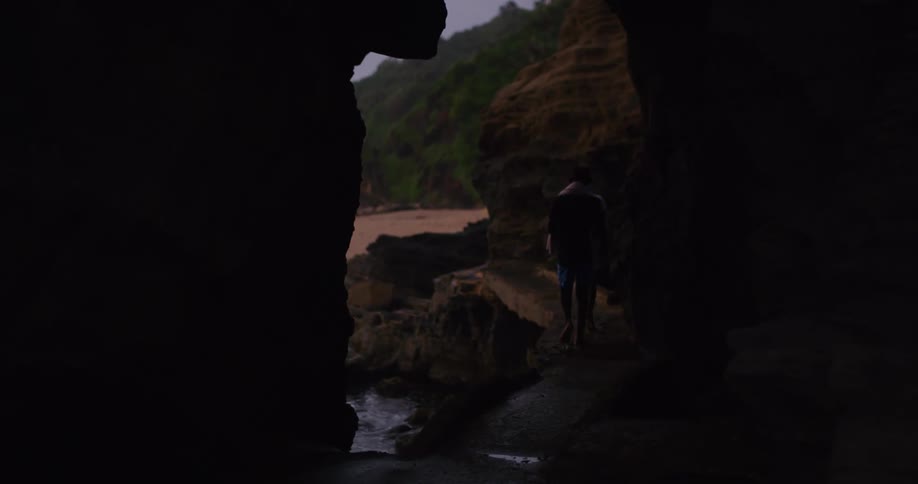 Two boys walk along the shore with towels over their shoulders