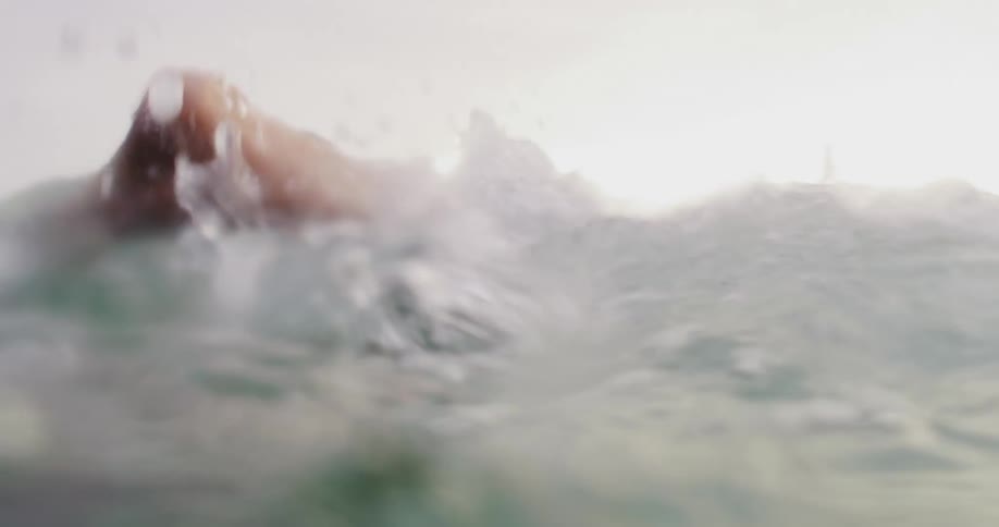 Two boys swimming in water with bubbles with land the sky and clouds in the background