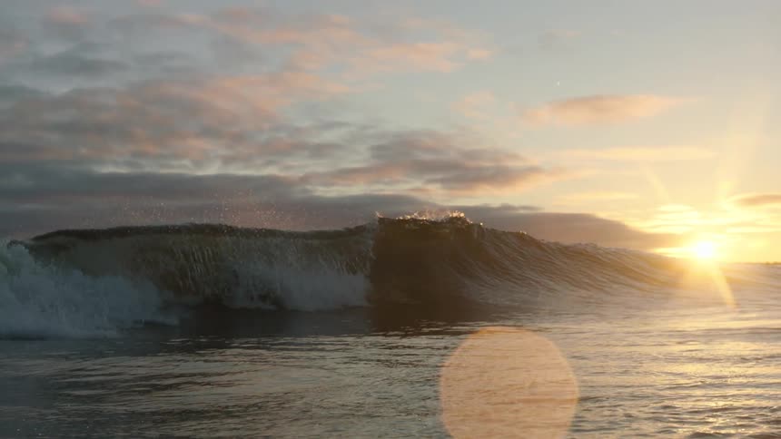 A large wave rolls over itself at sunset