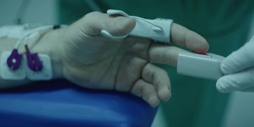 A doctor places an pulse oximeter on the finger of a patient