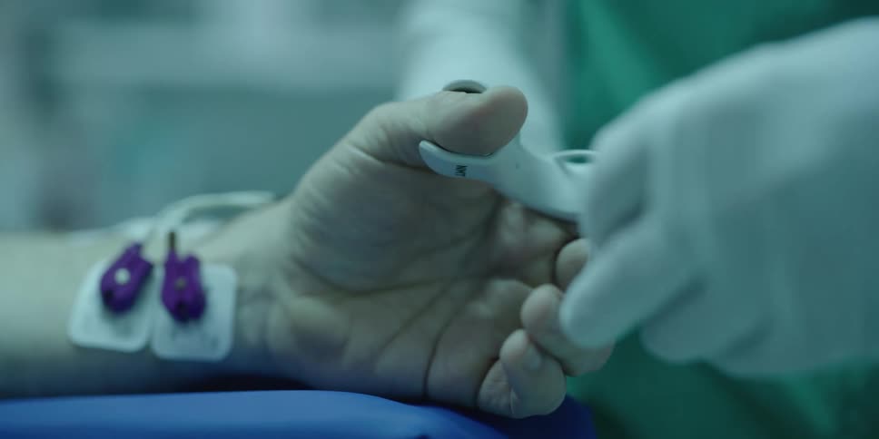 A doctor places a pulse oximeter on the finger of a patient in a hospital