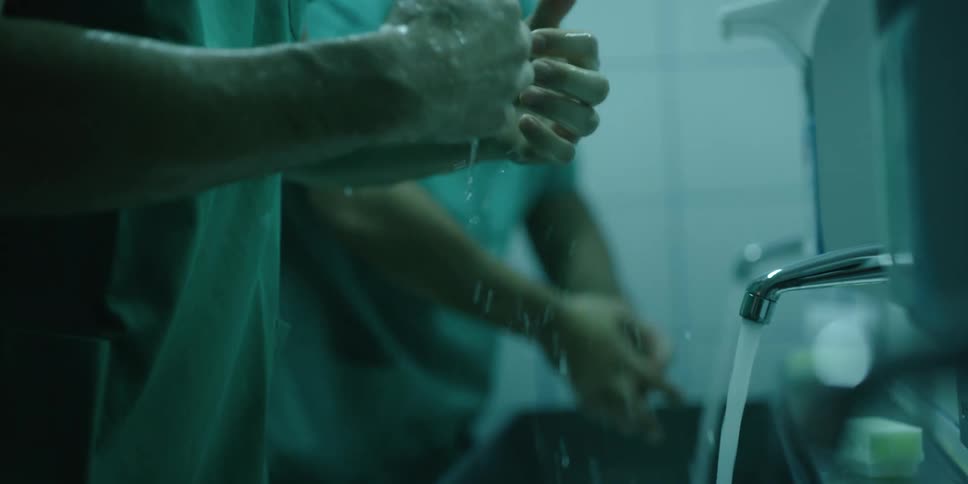 A pair of doctors wash their hands in a medical washing sink