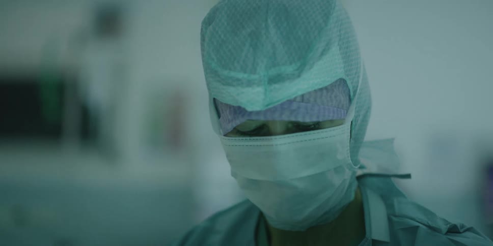 A doctor in personal protective equipment works in an operating room