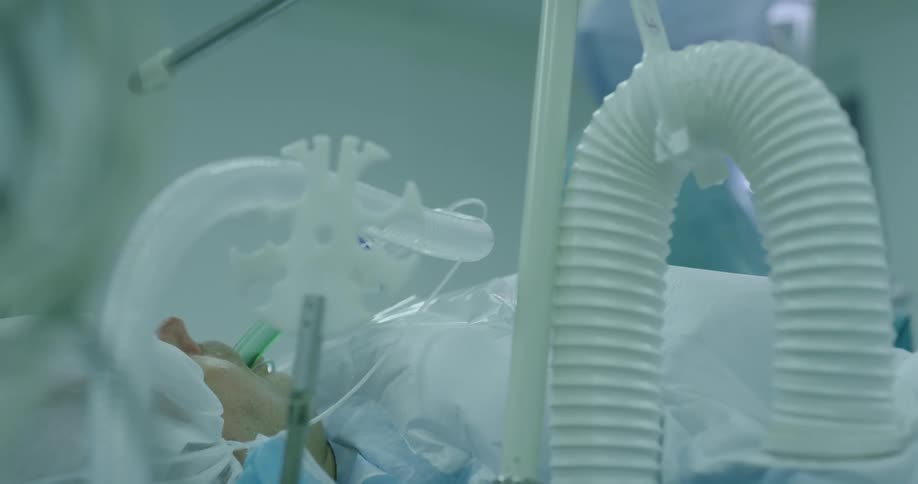 A patient is laying in the hospital with breathing tubes inserted