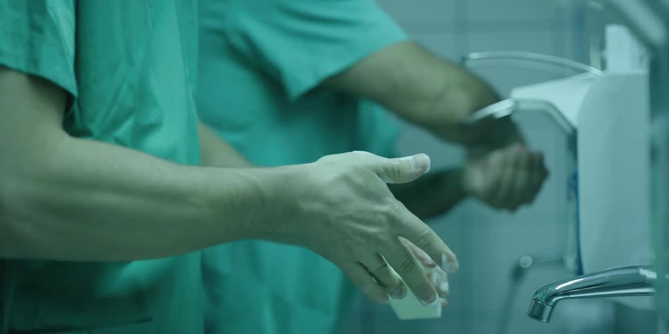 A pair of doctors wash their hands in a medical washing sink
