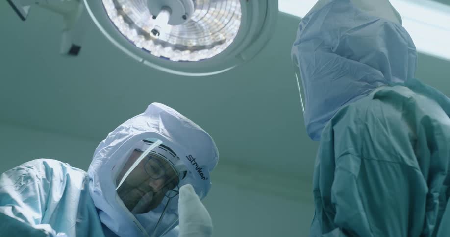 Surgeons in protective gear operating inside a surgery room