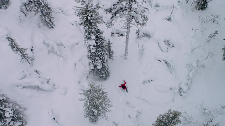 A person wearing red treks through snowy terrain