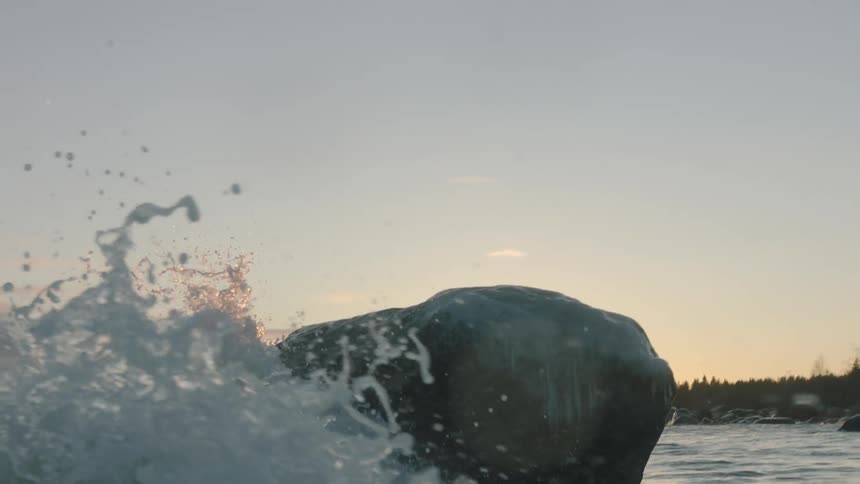 Waves crash against a boulder