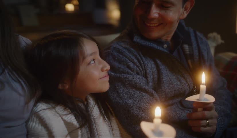 A man a woman and girl sitting on a couch holding candles