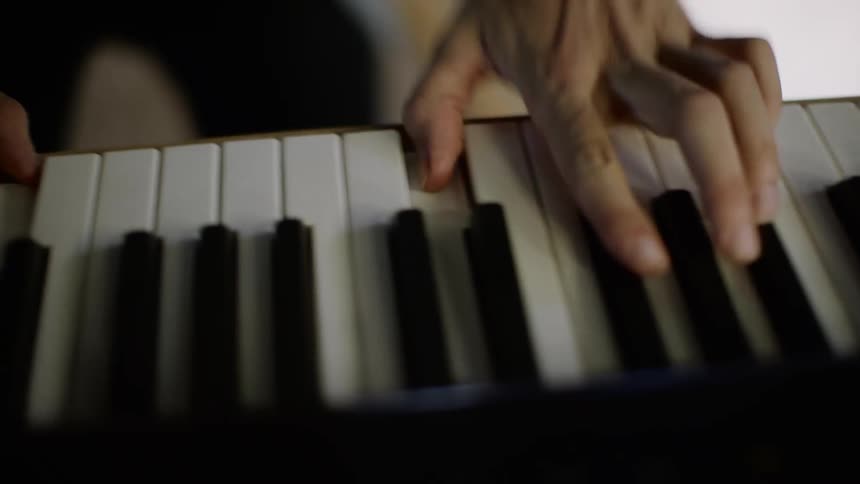A person is standing in a room and playing the piano