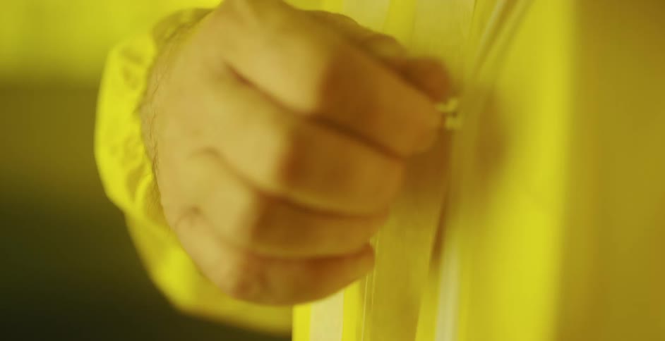 An older man is zipping up a yellow raincoat