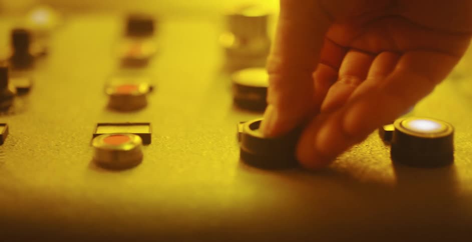 A person presses a button on a control panel under a yellow light