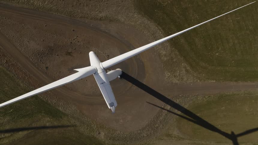 Top down view of a wind turbine just above the arc of its spinning blade tips