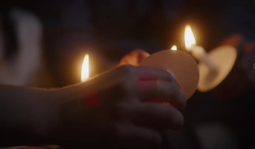 Couple holding candles while praying on a vigil at night