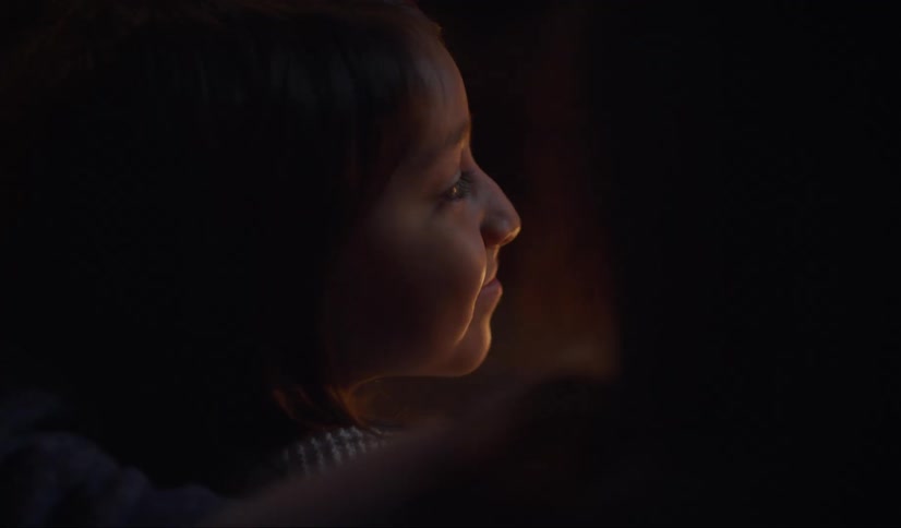 A woman turns to smile at someone then looks back at a lit candle