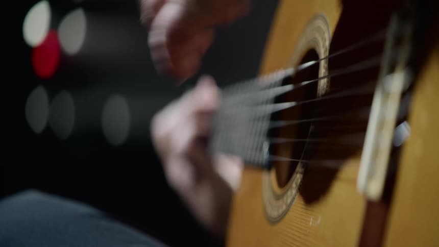 A sitting guitarist strums the guitar