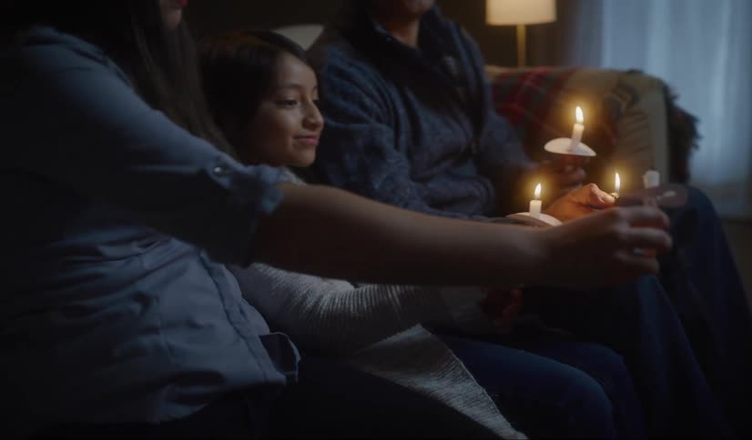 Family sitting in a couch at night light candels to pray in vigil