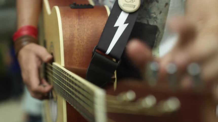 A man is playing the guitar outdoors during the day