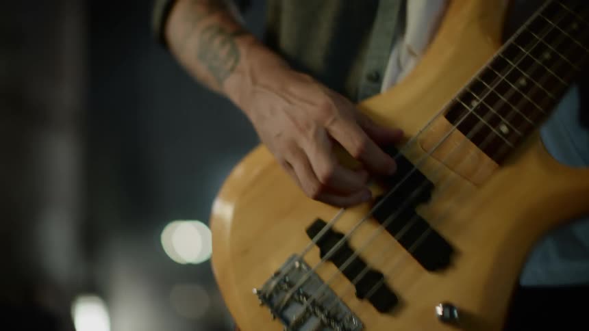 A man in a room playing a guitar with a wall in the background