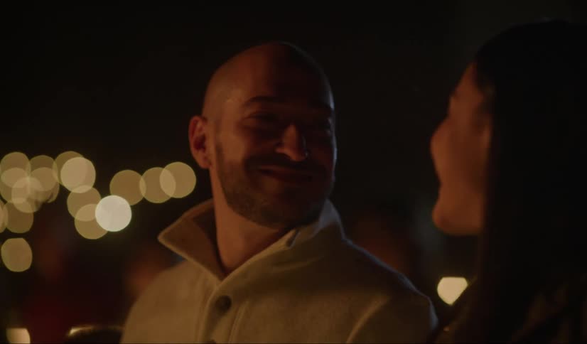 A couple smile at each other and kiss in a romantic setting outdoors