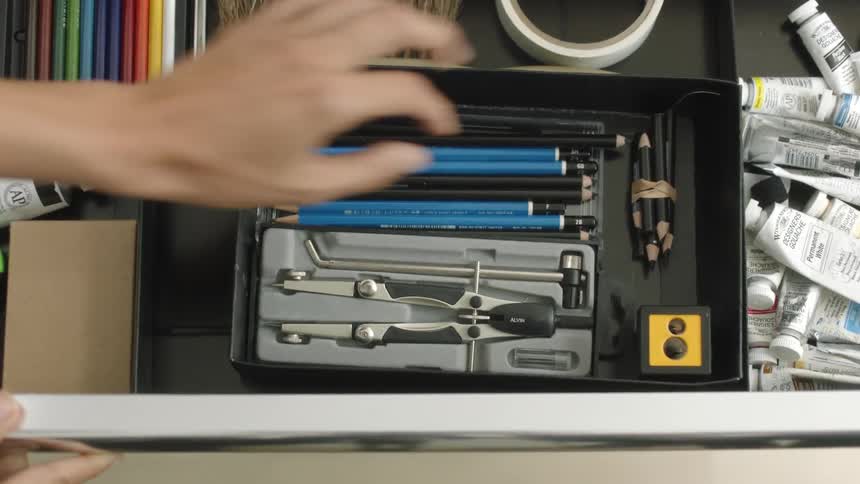 A woman opens a drawer and pulls out a pencil