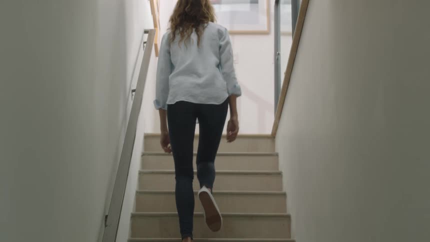 A woman walks up the steps at home