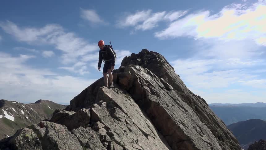 A man is walking across the top of a rock mountain